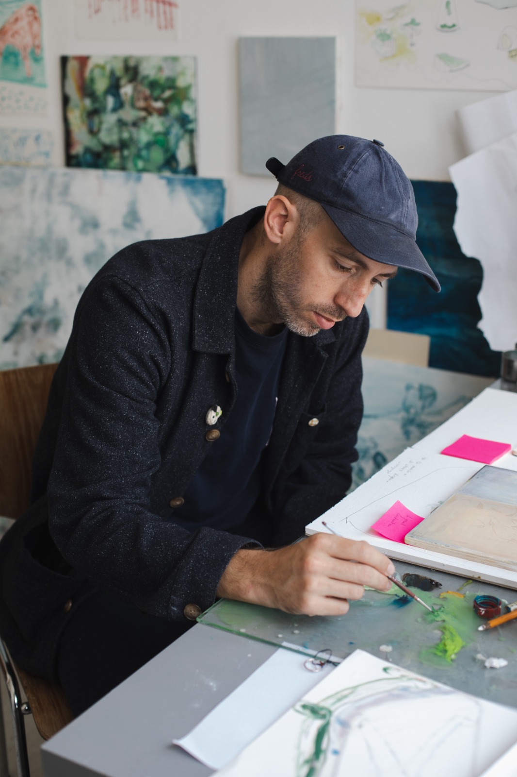 Fred Vincent in his studio, painting at a desk surrounded by works in progress